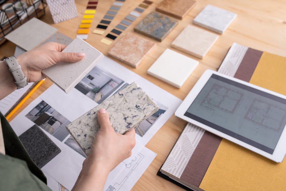 hands young female designer holding two samples marble tile wooden table with digital tablet photos home interior etc